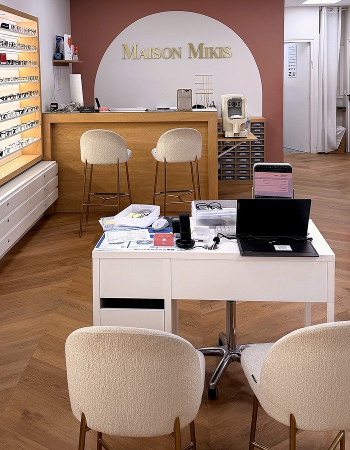 Intérieur chaleureux de la boutique Maison Mikis avec présentoirs de lunettes et comptoir en bois